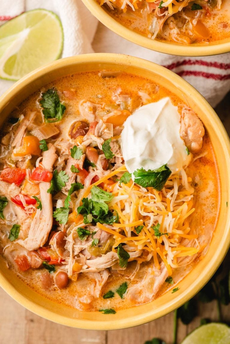 Bowl of slow cooker white chicken chili with sour cream and shredded cheese.
