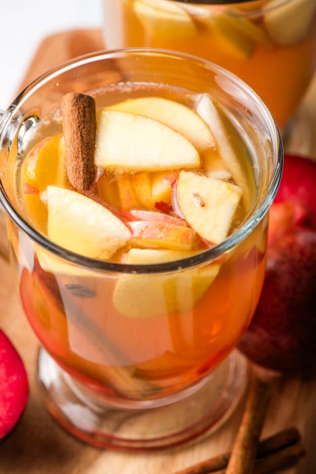 Fall sangria with apple cider, pears, apples, and cinnamon sticks in a glass mug.