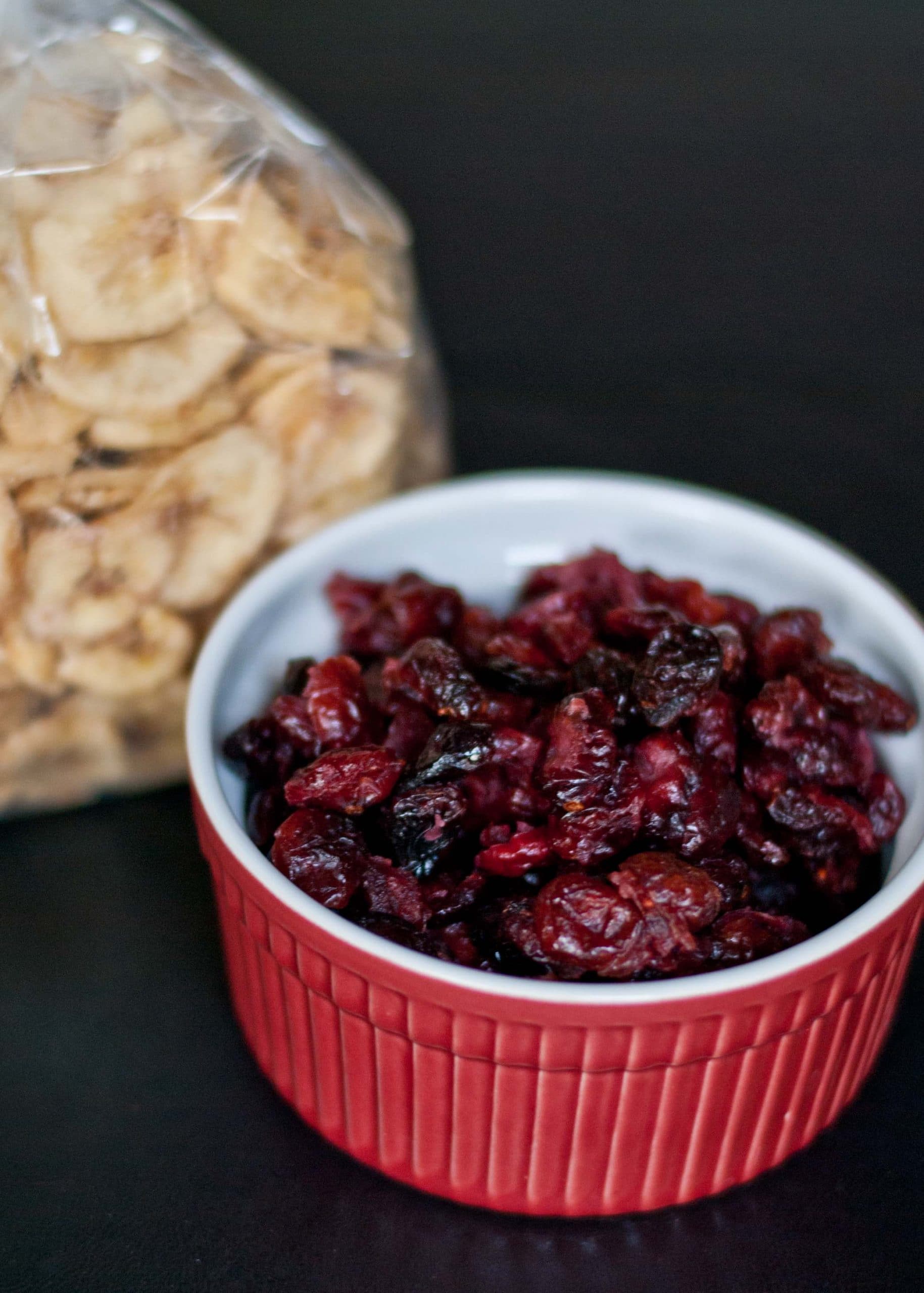small bowl of dried cherries and a bag of dried banana chips