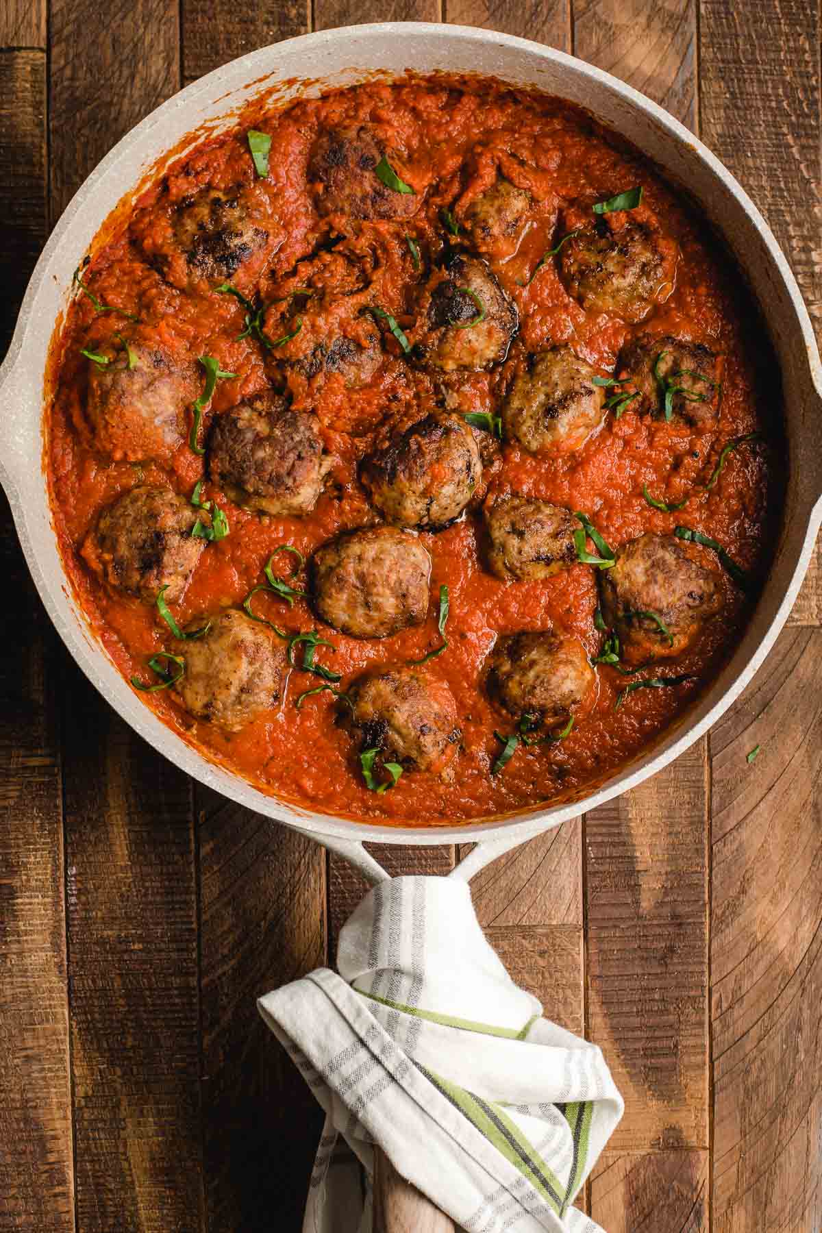 Traditional italian meatballs in tomato sauce in a large white skillet.