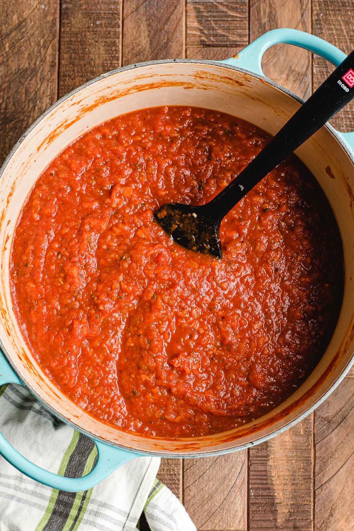 Wooden spoon stirring homemade tomato sauce.