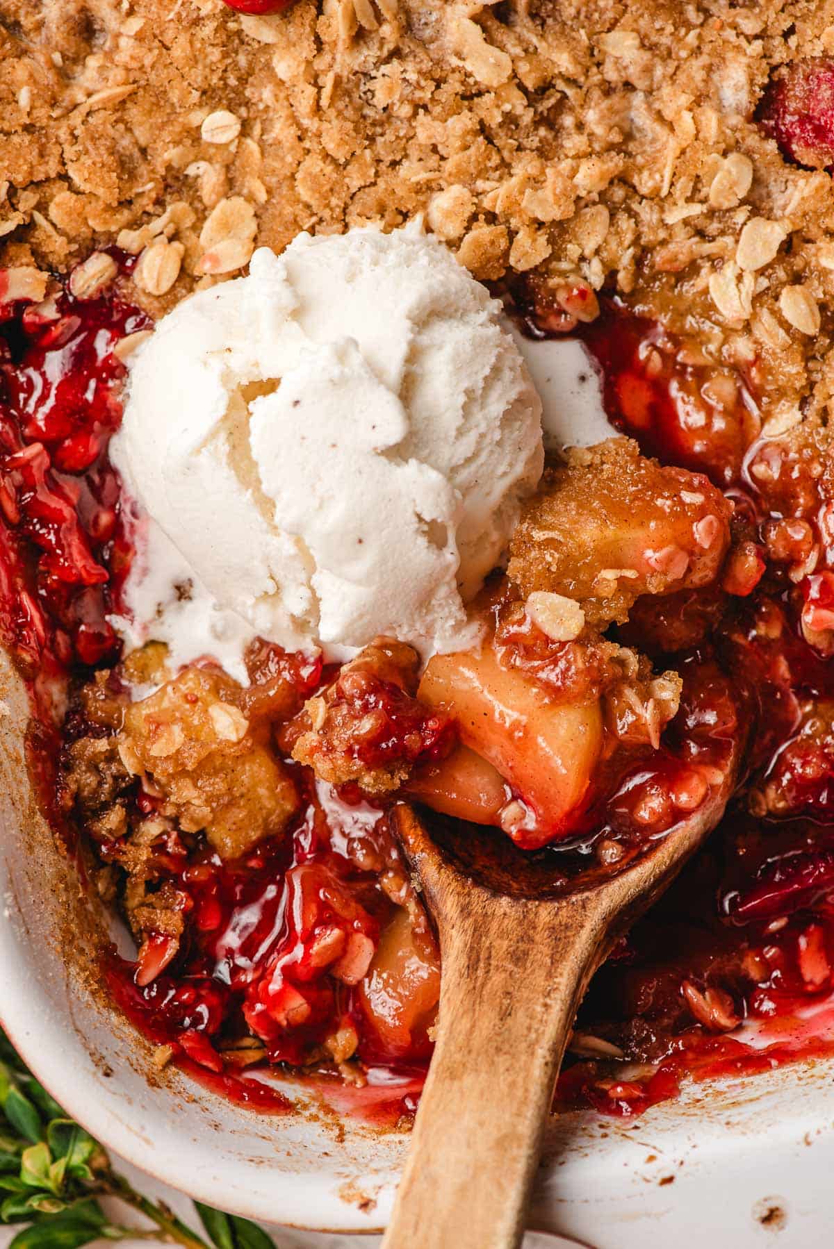 Baking dish with cranberry apple crisp, topped with ice cream.