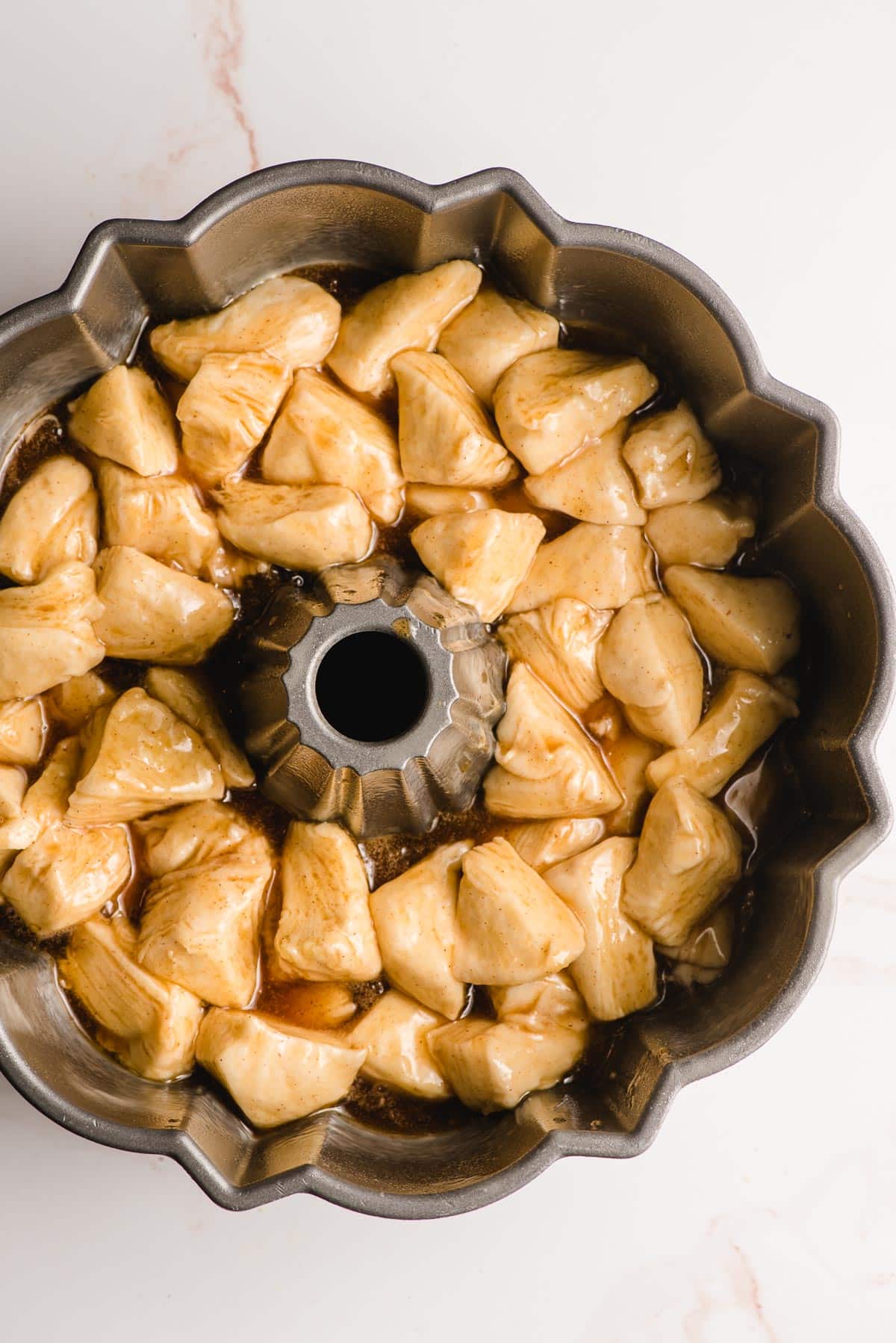 Unbaked monkey bread with canned biscuits shown in a bundt pan.