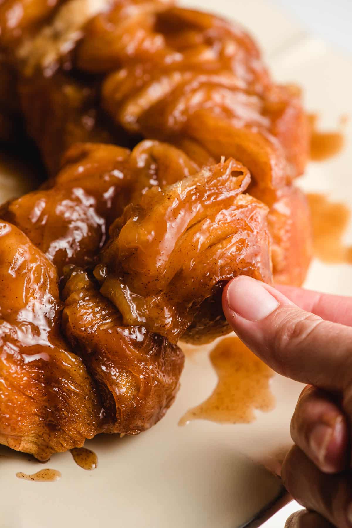 Fingers pulling a piece of monkey bread off the loaf.