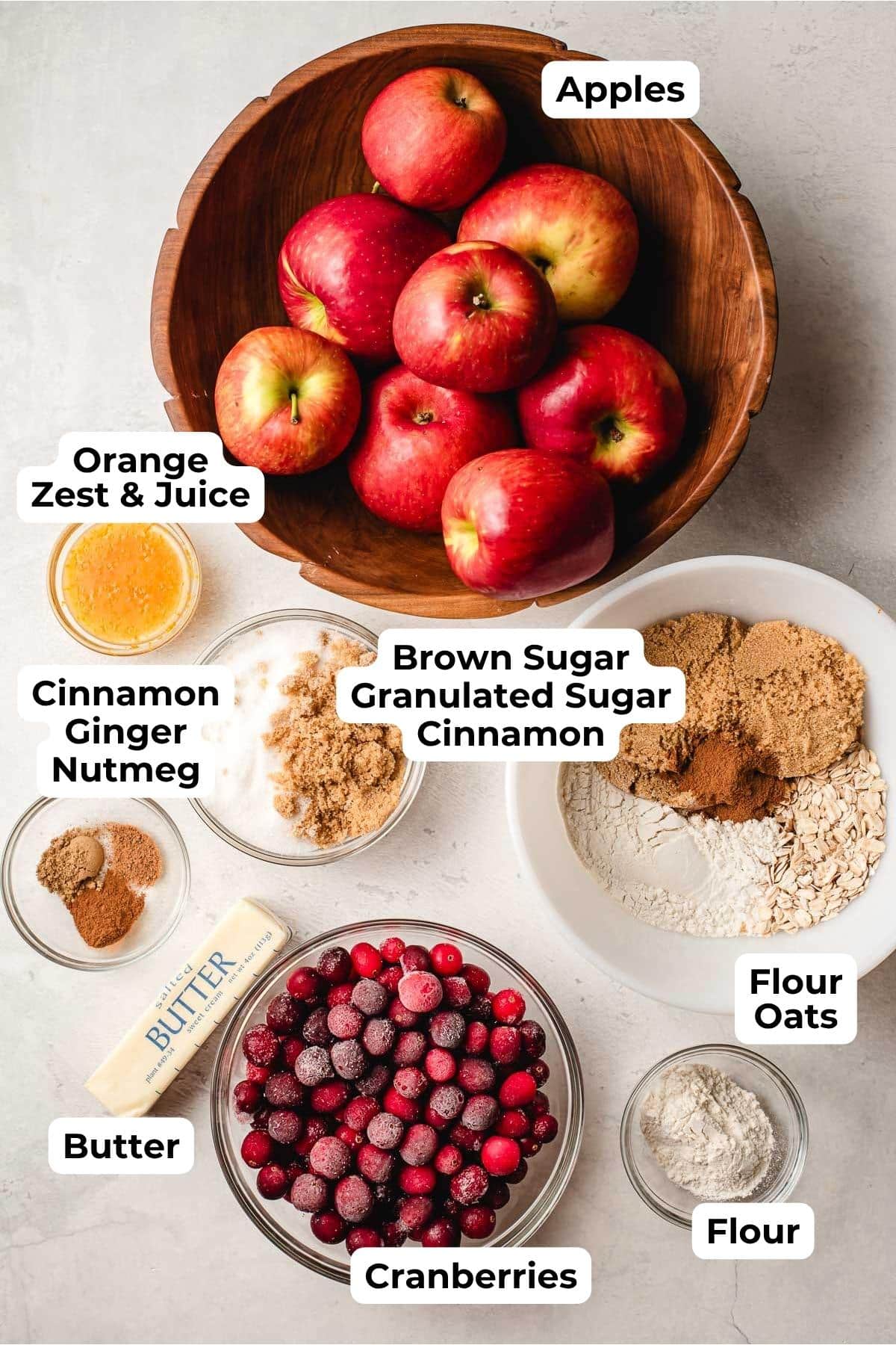 Bowl of apples, cranberries, orange juice, spices, flour, and sugar.