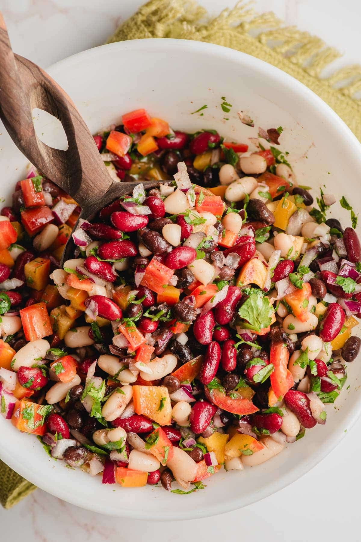 Wooden spoon scooping up bean and cilantro salad.