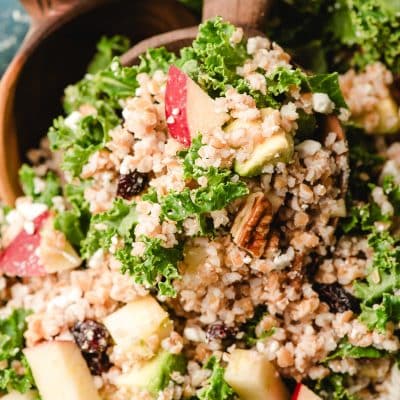 Wooden spoon scooping bulgur salad out of a bowl.