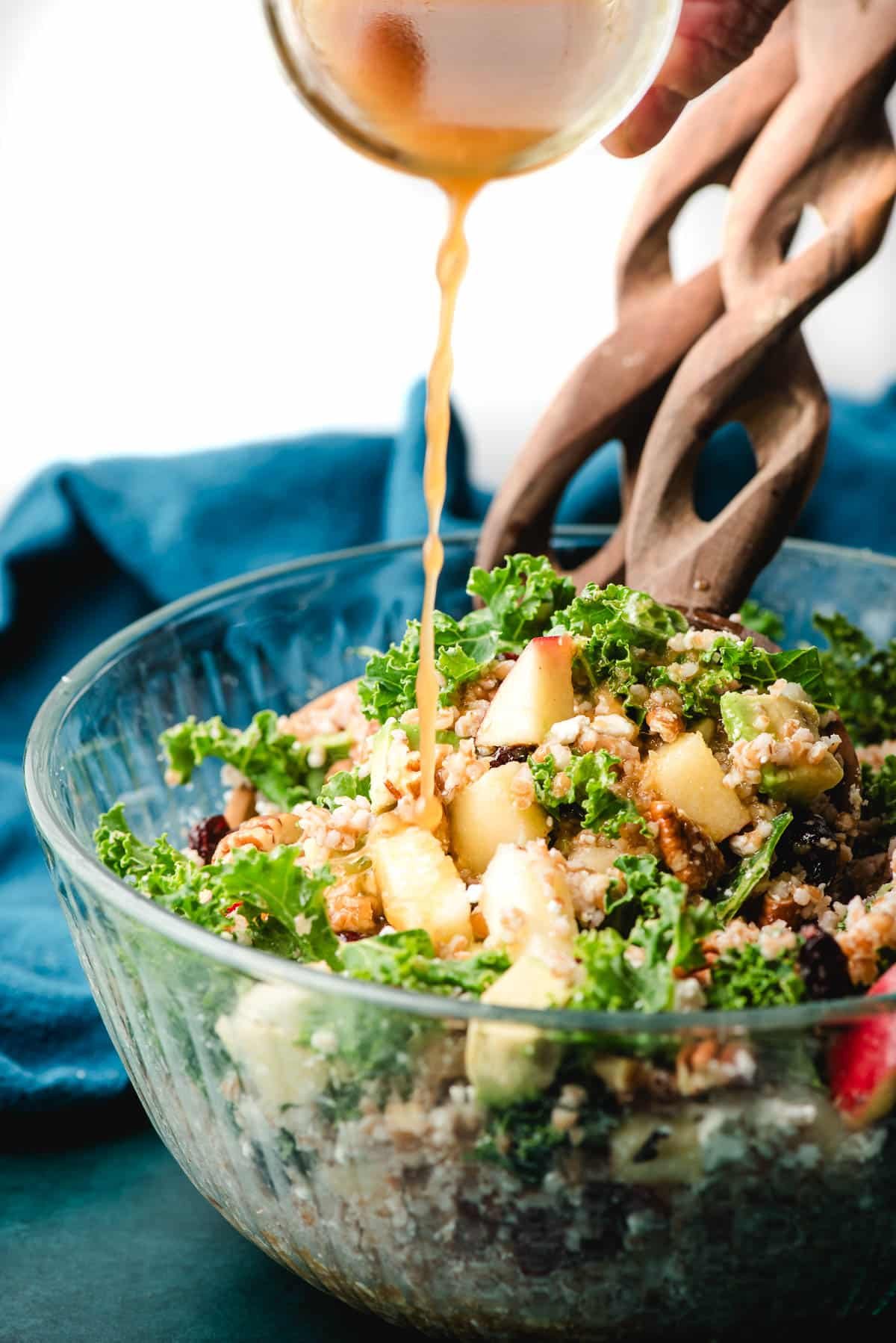 Orange vinaigrette being poured over a bulgur salad.