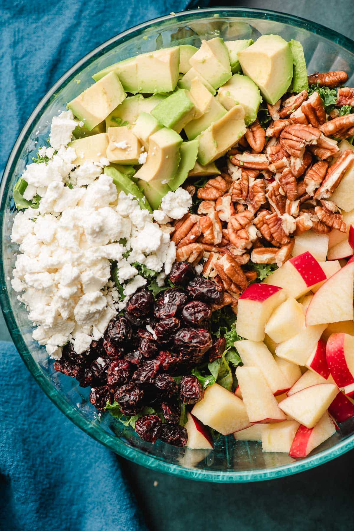 Bowl filled with bulgur, goat cheese, dried cranberry, apple, pecans, and avocado chunks.