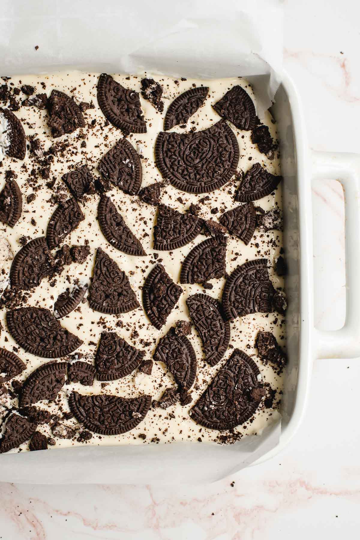 Unbaked cheesecake with broken pieces of Oreo on top.