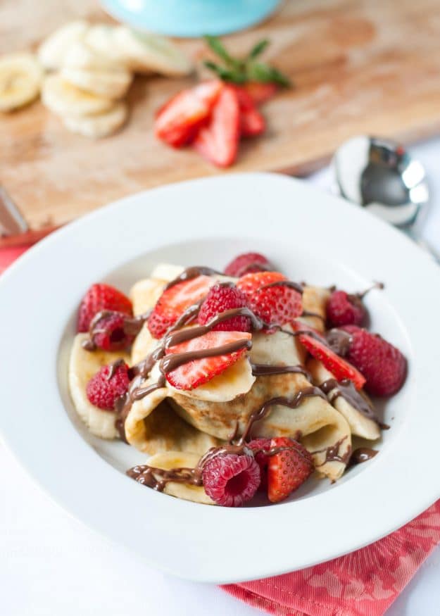 Ice Cream Stuffed Crepes with a drizzle of nutella and strawberry and banana slices on top.