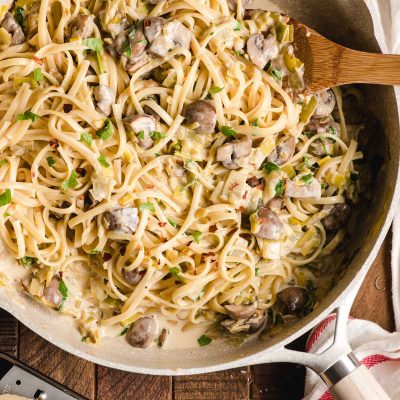 Linguine, mushrooms, and leeks in a cream sauce in a large saute pan.