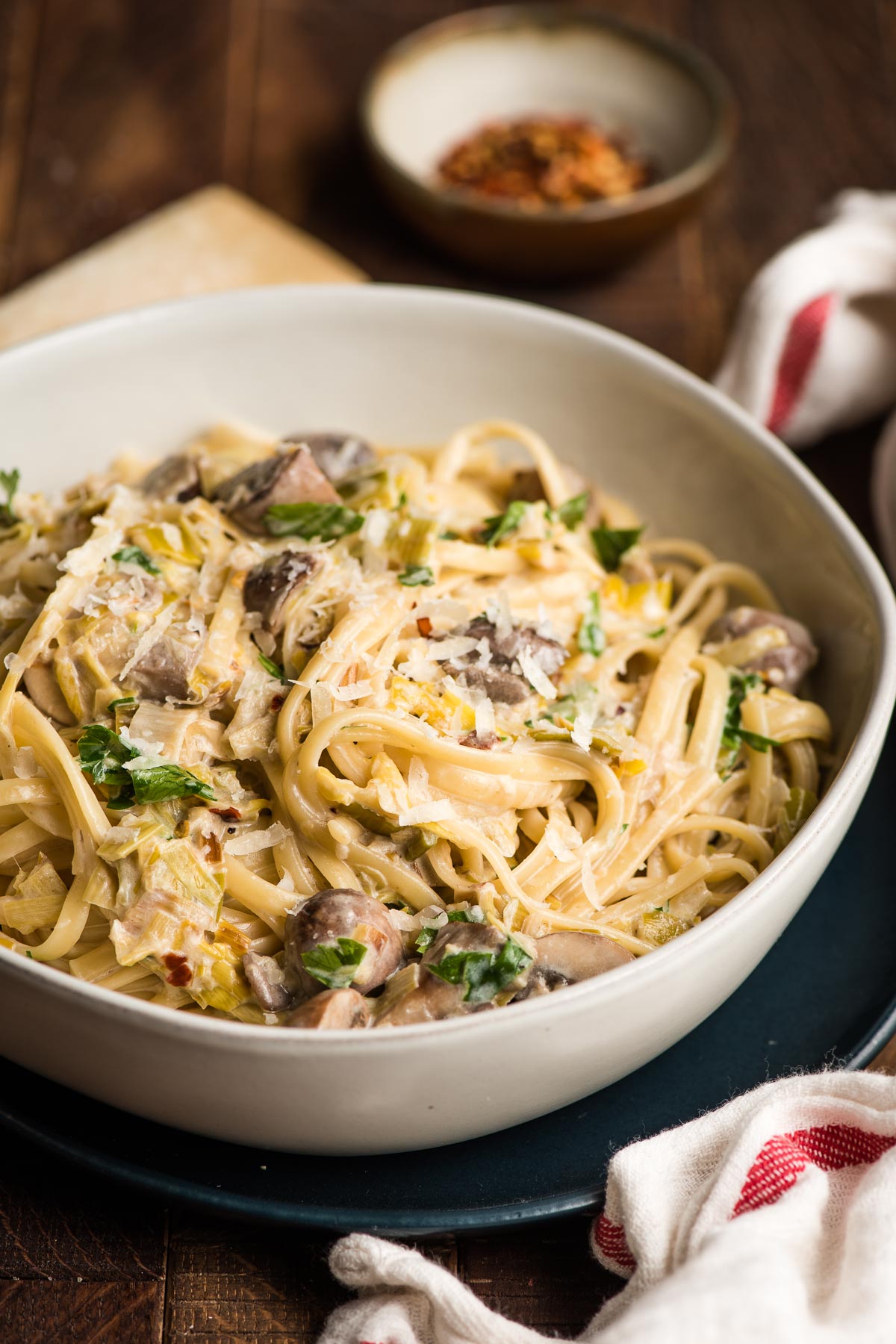 White bowl filled with linguine, mushrooms, and leeks in a creamy sauce.