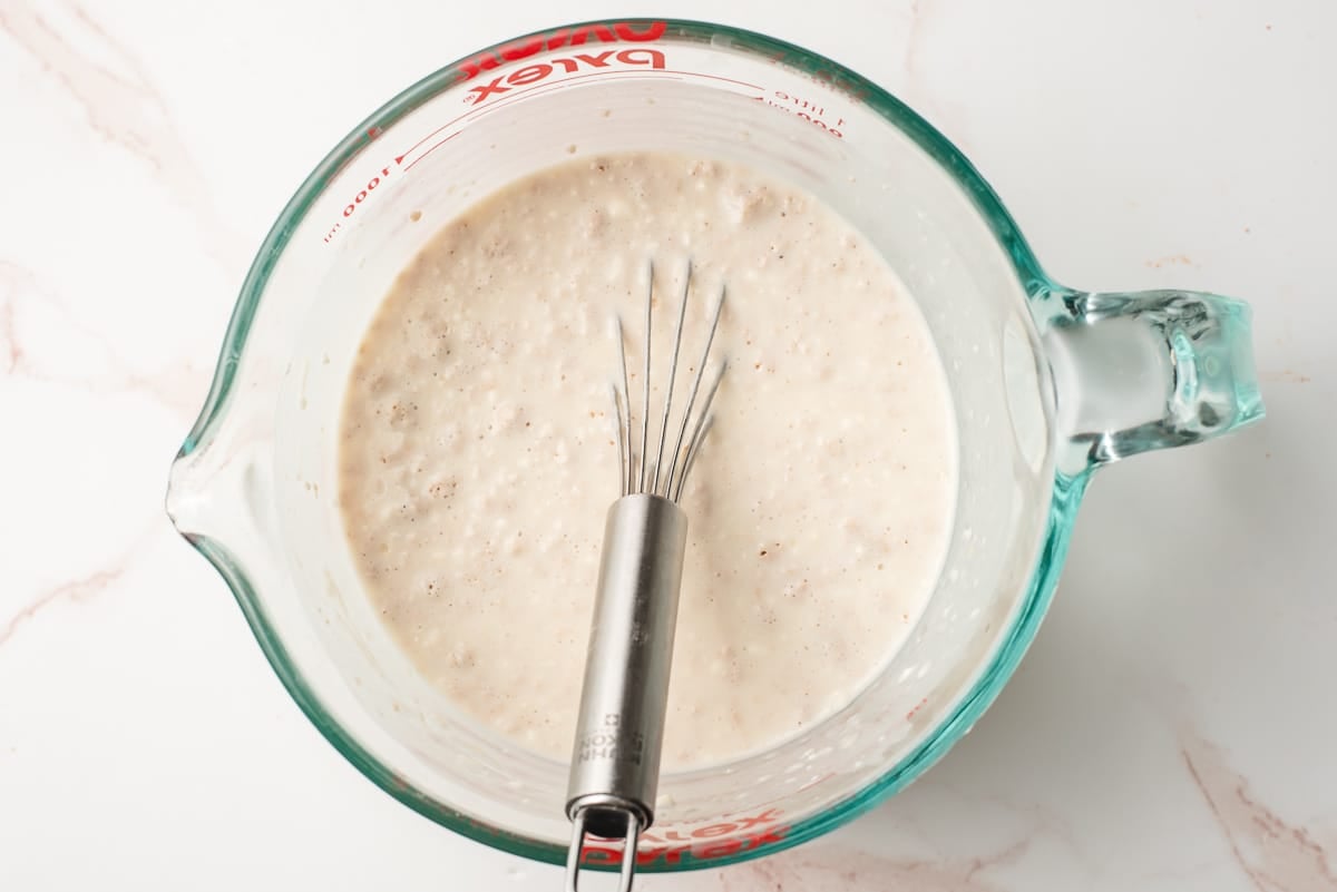 Yeast, milk, sugar, and flour whisked together in a measuring cup.