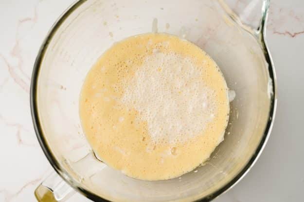 Yeast starter added to eggs in a glass mixing bowl.