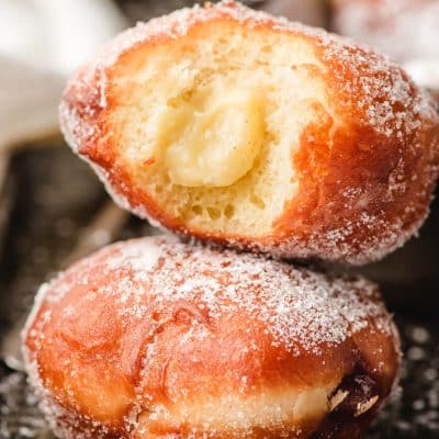 Custard filled paczki with a bite taken out of it.