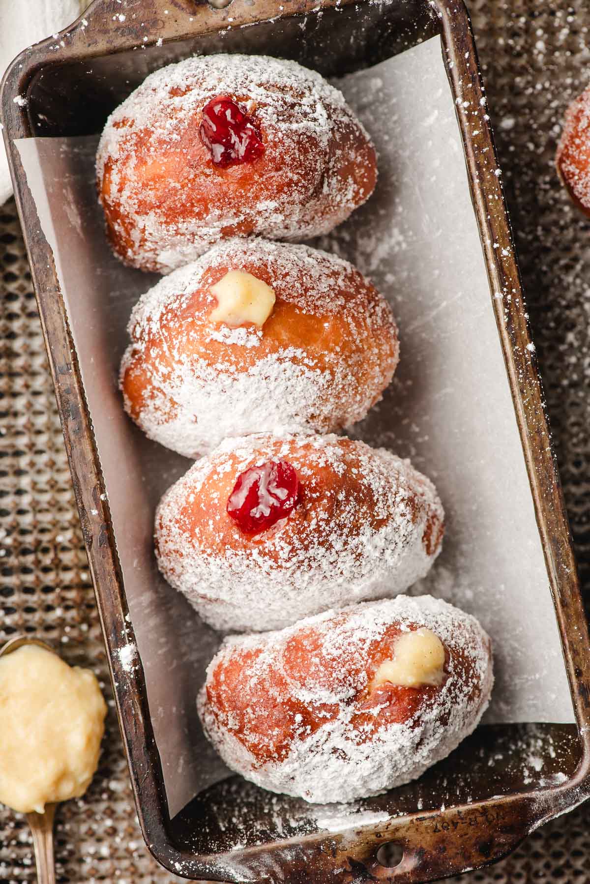 Loaf pan filled with four paczki donuts.