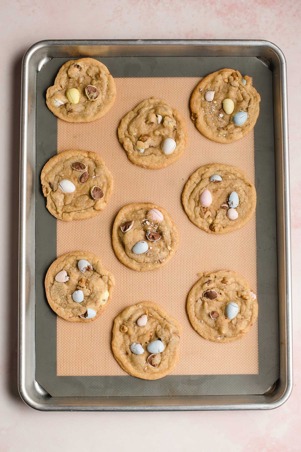 Baked mini egg cookies on a silicone mat on a baking sheet.