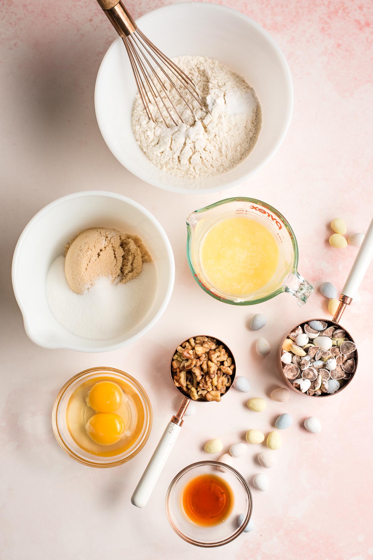 Ingredients for cookies shown in bowls--flour, sugars, eggs, vanilla, butter, walnuts, and mini chocolate eggs.