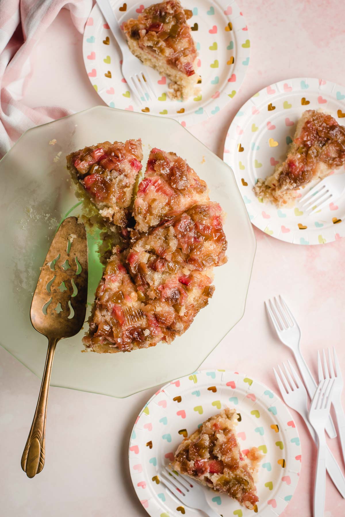 Rhubarb upside down cake on a pale green platter with a vintage gold cake server.