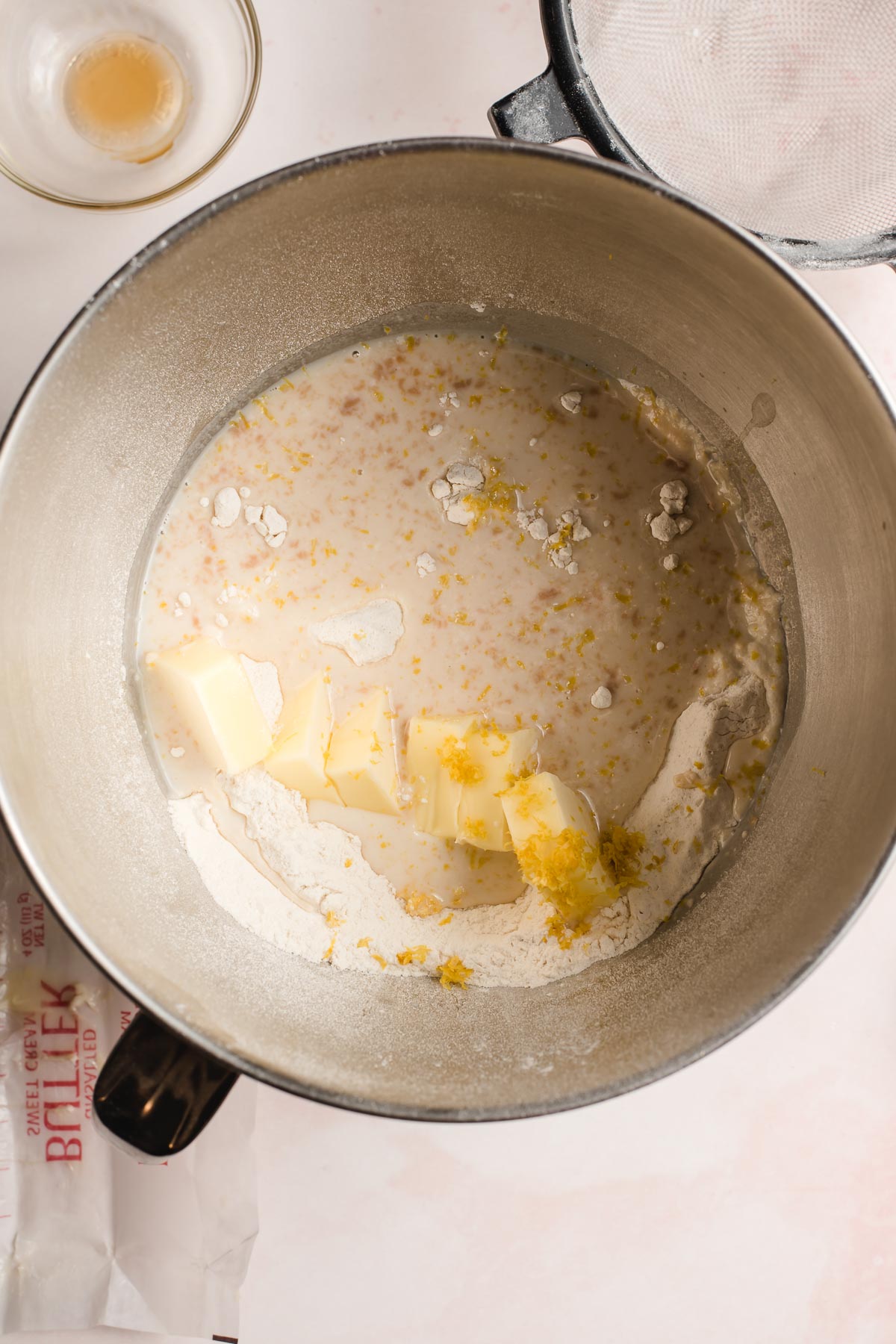 Chunks of butter, vanilla, and lemon zest being worked into flour.