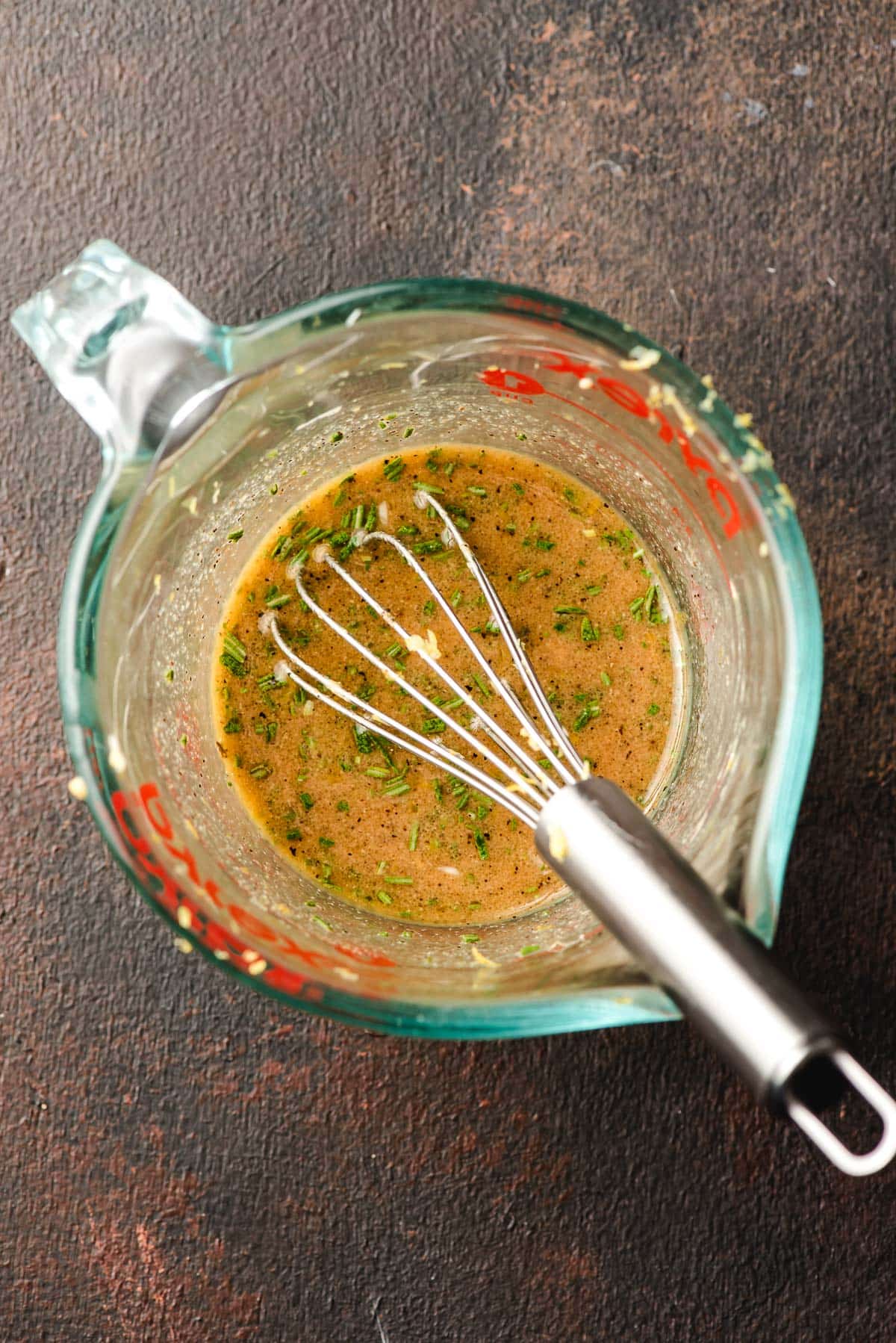 Balsamic, olive oil, rosemary, garlic, and salt and pepper whisked together in a glass measuring cup.