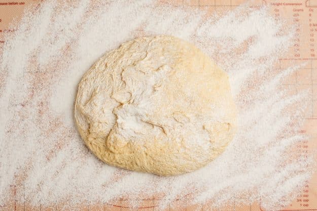 Orange sweet roll dough on a floured baking mat.