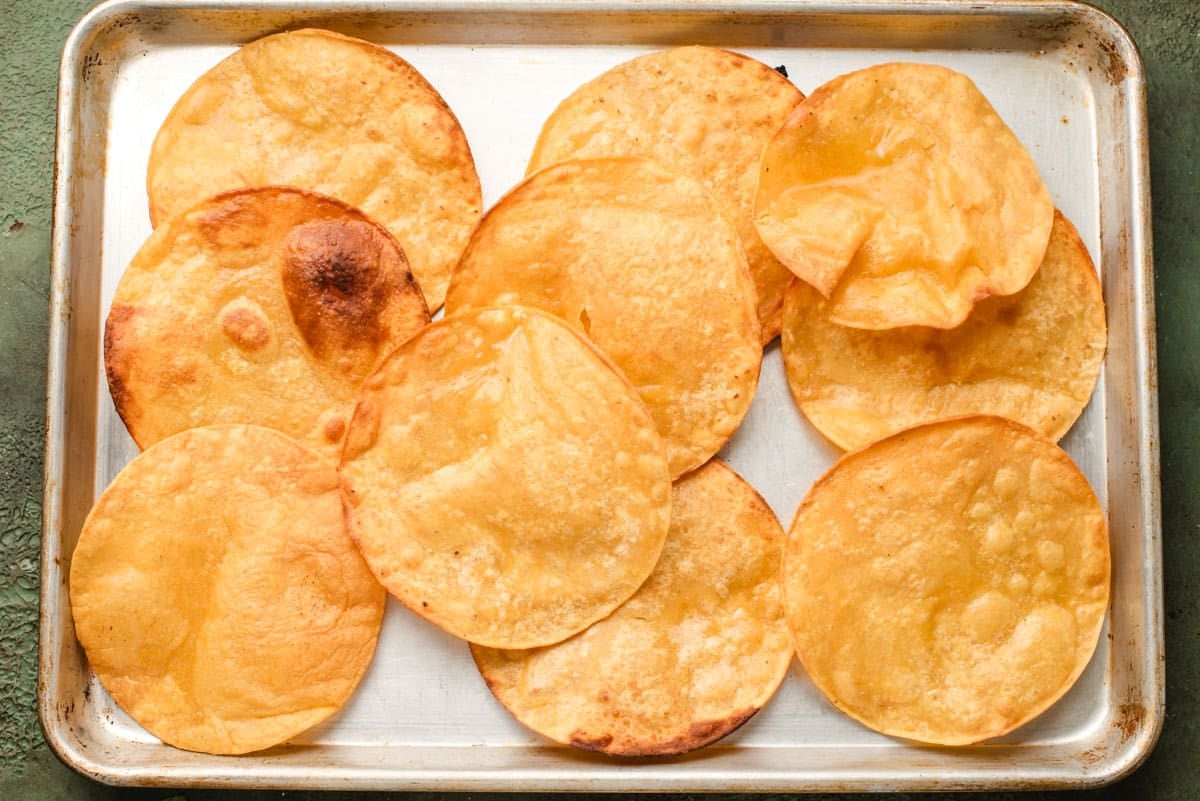 Deep fried tostada shells on a sheet pan.