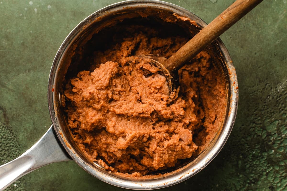 Refried beans with seasonings in a sauce pan.
