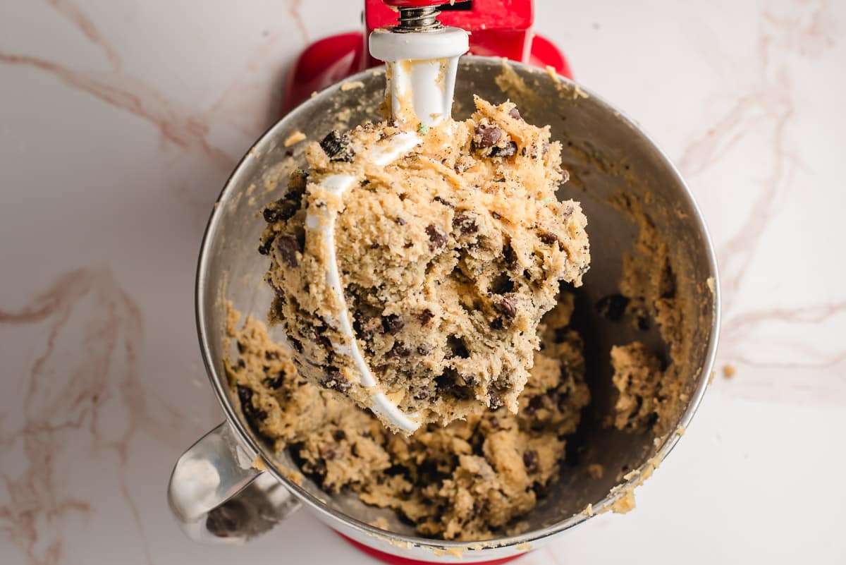 Mint oreo chocolate chip cookie dough in an electric mixing bowl.
