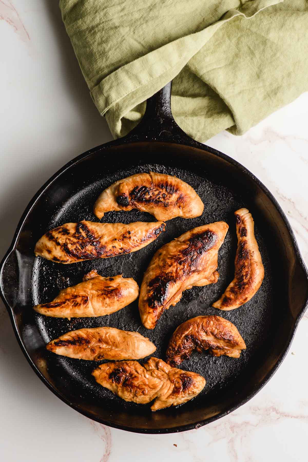 Chicken breast tenderloins shown cooked in a cast iron skillet.