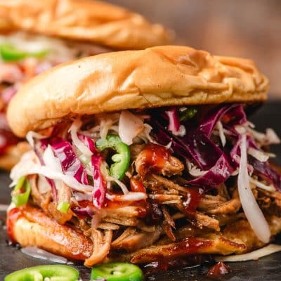 Spicy pulled pork sandwich loaded with coleslaw and BBQ sauce.