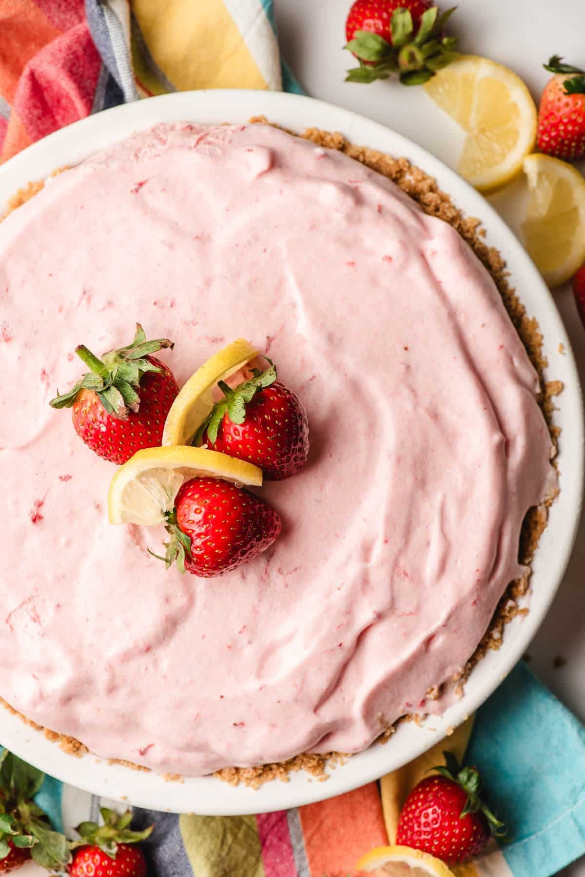 Frozen strawberry lemonade pie topped with fresh strawberries and lemon slices.