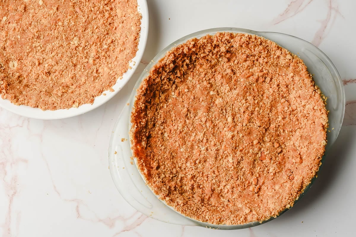 Two glass pie pans with graham cracker crusts.