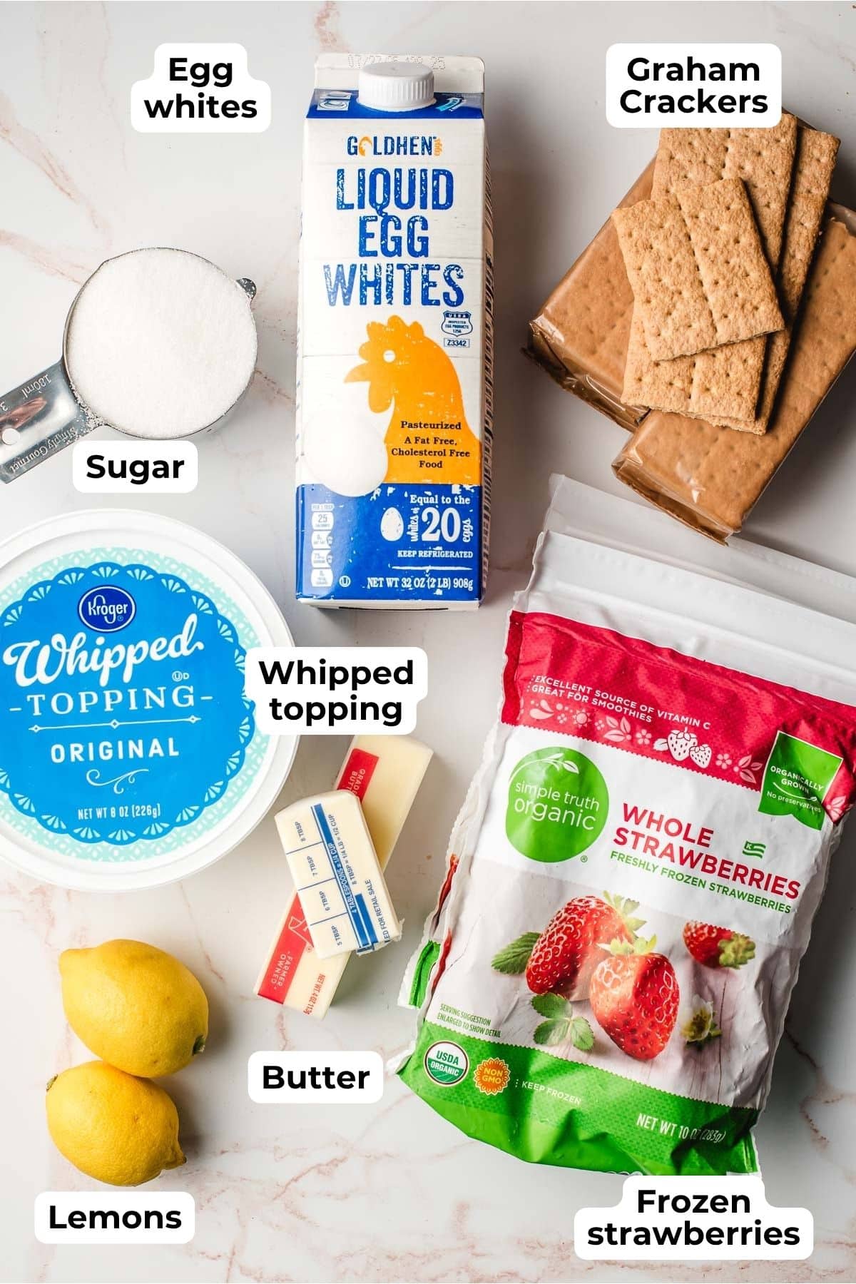 Sugar, pasteurized egg whites, graham crackers, whipped topping, lemons, butter, and frozen strawberries on a white background.