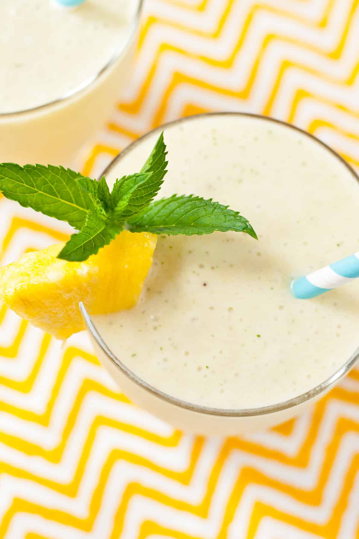 Smoothie in a glass garnished with a piece of pineapple and mint.