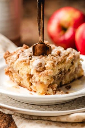 Fork stabbing into a slice of apple crumb cake.