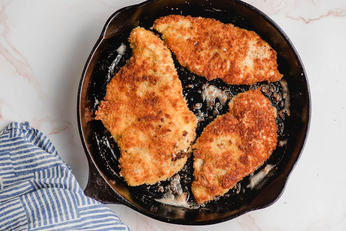 Panko crusted chicken being browned in a cast iron skillet.