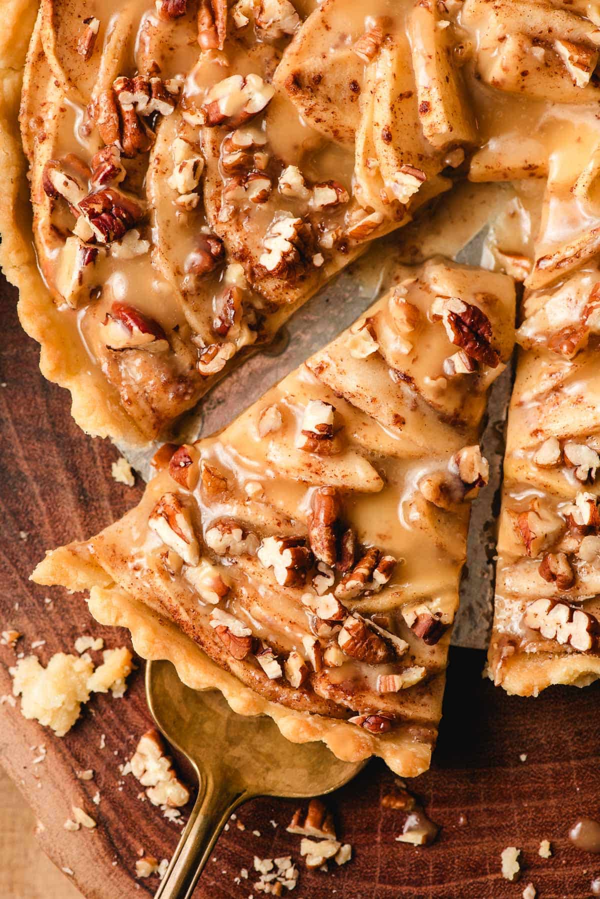 Slice of maple caramel apple tart topped with pecans.