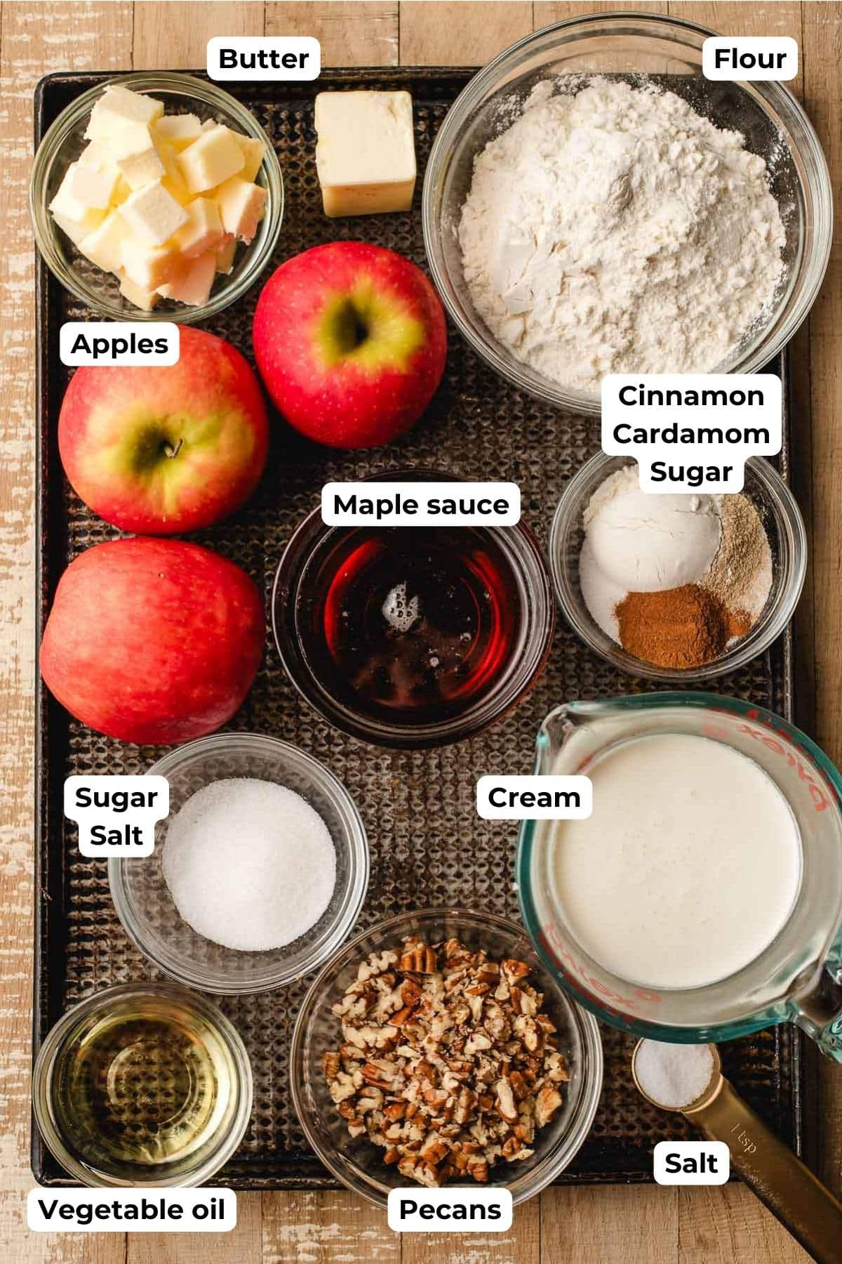 Butter, flour, spices, apples, maple syrup, cream, oil, pecans, and salt on a sheet pan.