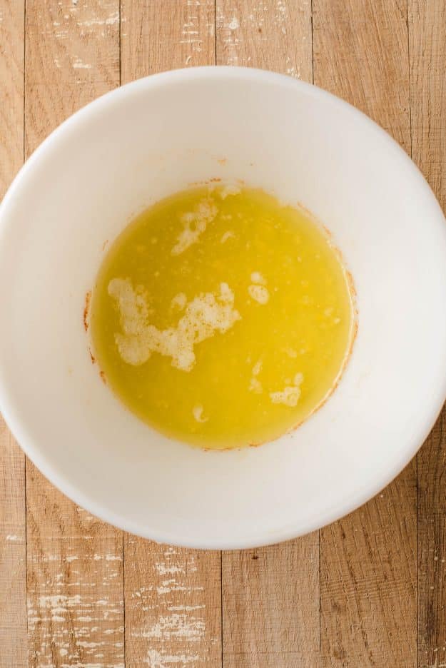 Melted butter, oil, salt, and sugar in a white bowl.