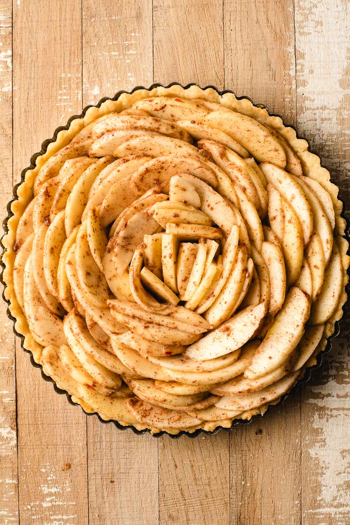 Tart pan lined with sliced apples in concentric circles.