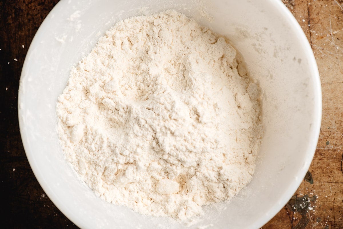 Butter cut into a flour mixture in a white bowl.