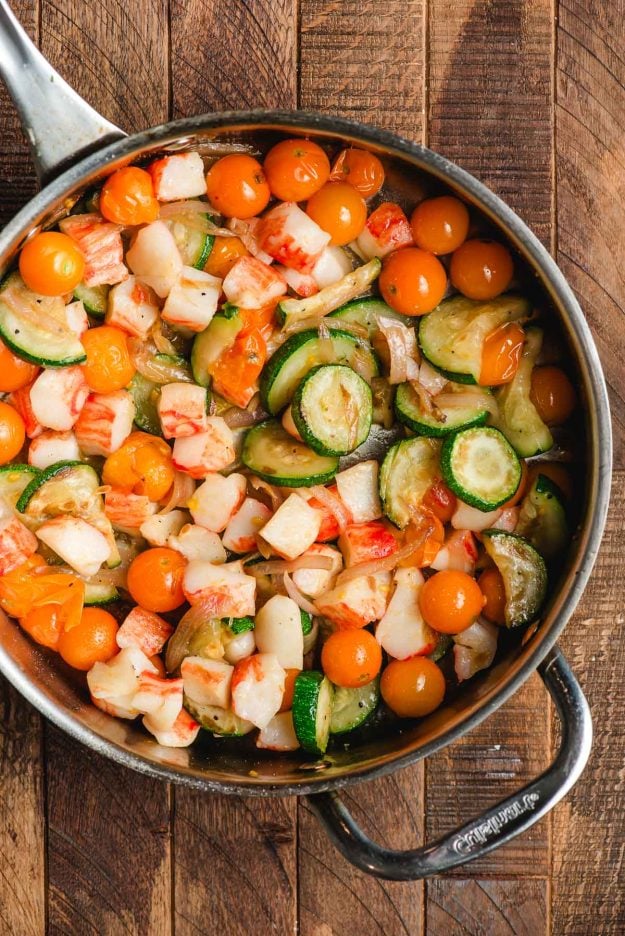 Zucchini, crab, shallots, and cherry tomatoes sauteed in a skillet.