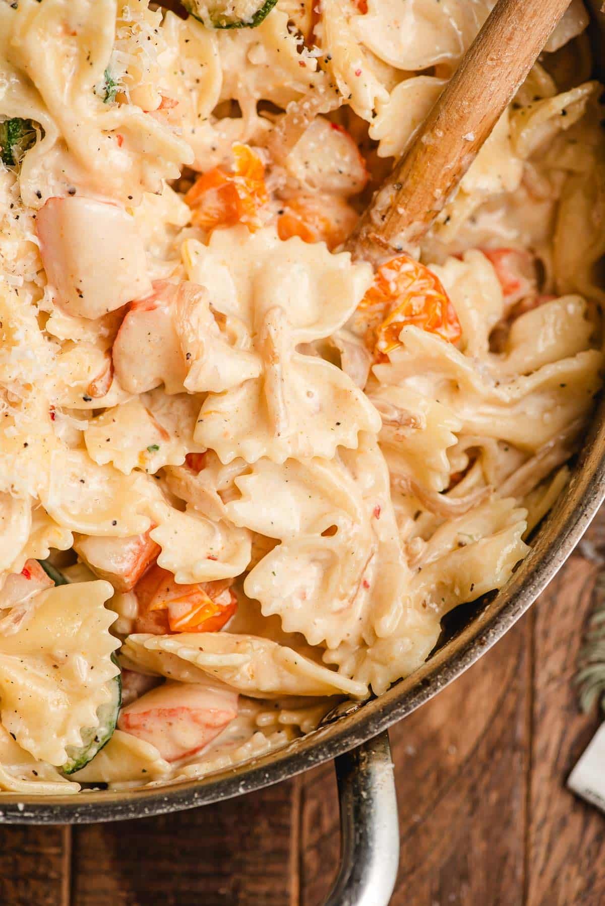Bowtie pasta with cherry tomatoes and imitation crab in a skillet.