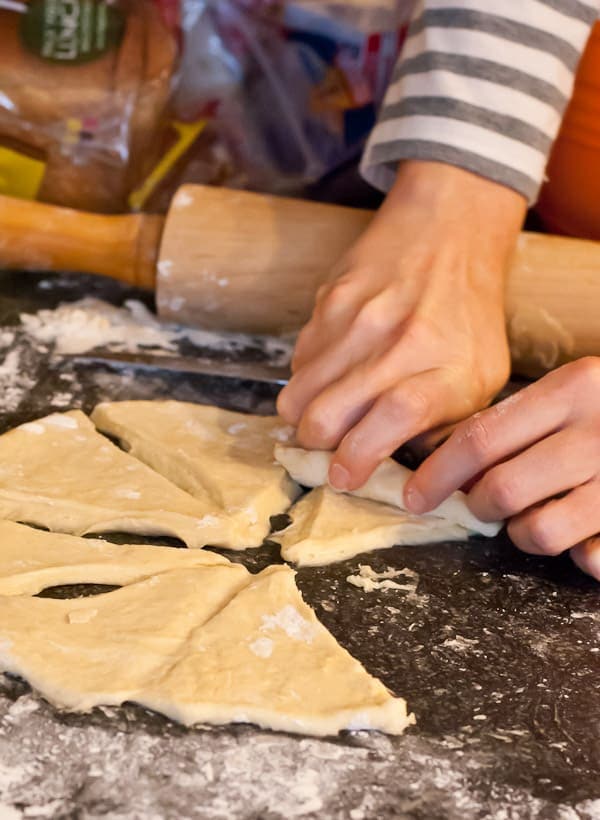 slices of butterhorn dough are rolled up into a crescent roll shape