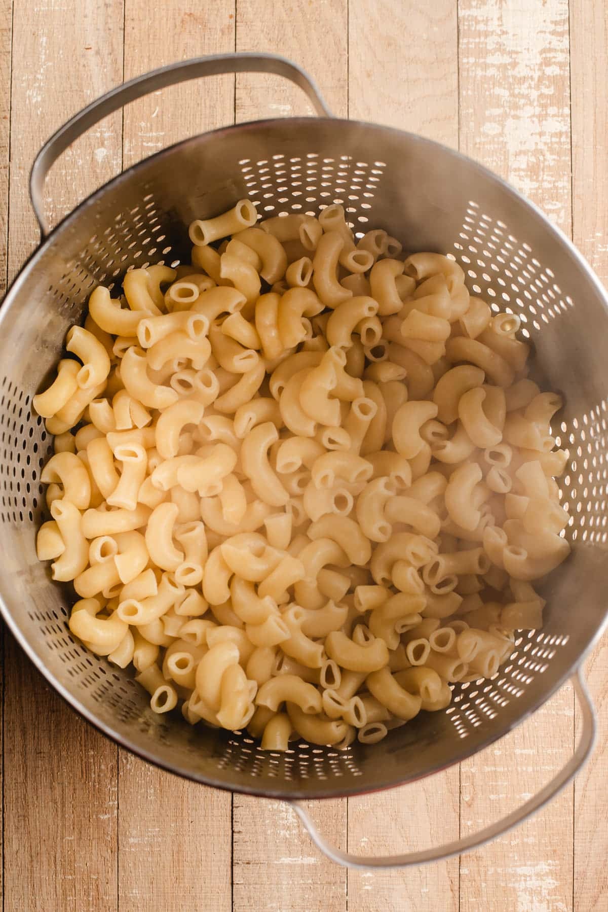 Boiled macaroni noodles in a colander.