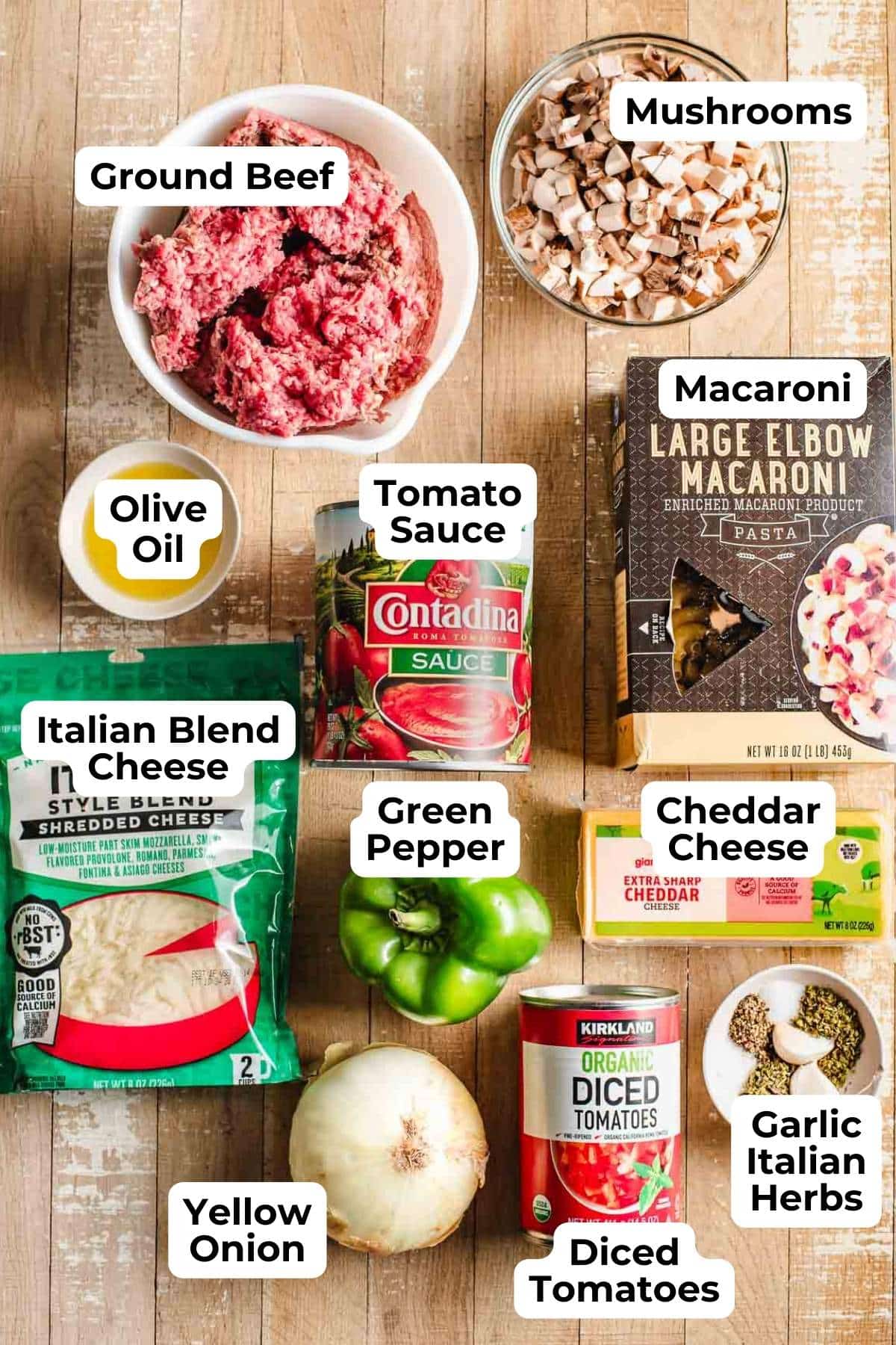 ground beef, mushrooms, green pepper, macaroni, cheeses, onion, canned tomatoes and sauce, plus seasonings on a wood background.