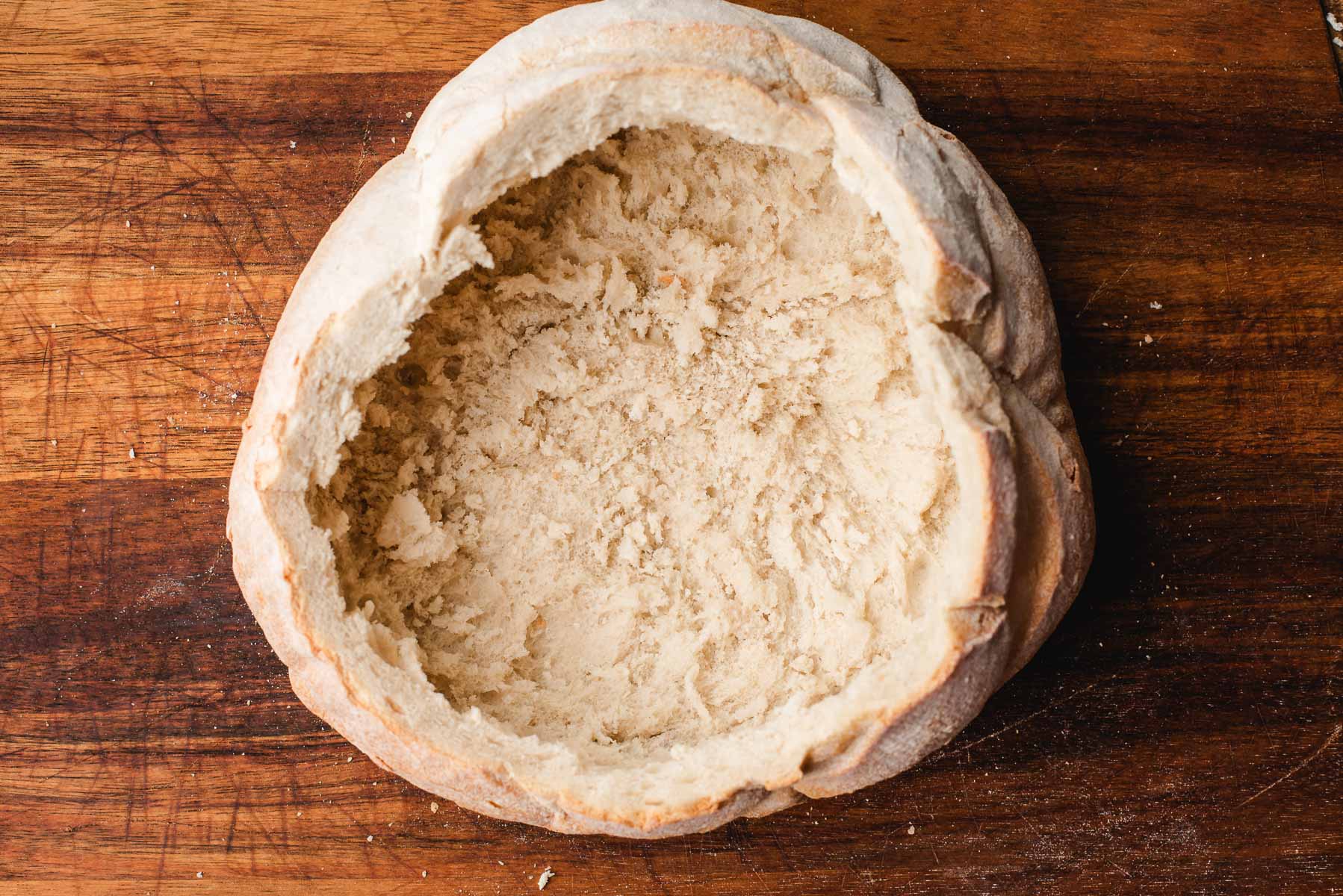 Round sourdough bread loaf with the center carved out and removed to make a bowl.