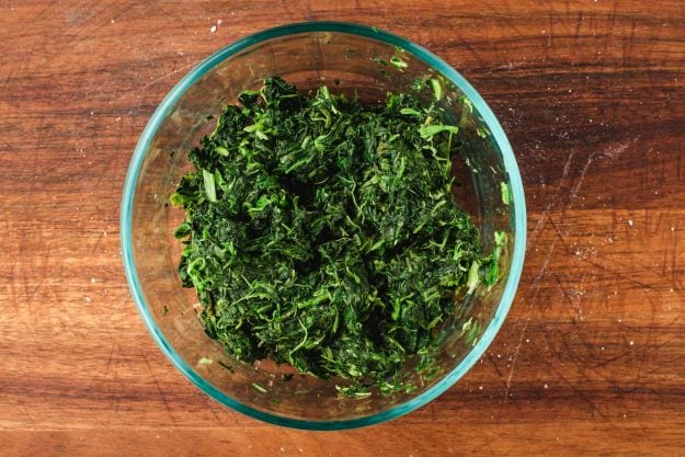 Bowl of thawed and drained frozen spinach.
